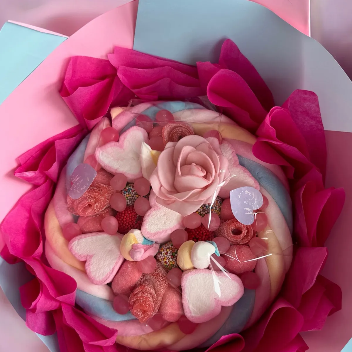 Bouquet de bonbons rose emballé dans du papier de soie fuchsia, photographié au magasin